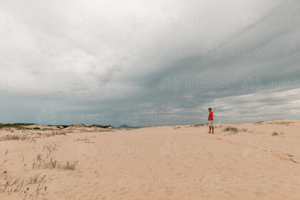 Man exploring sand dunes at Mungo Beach on the NSW coast - Australian Stock Image