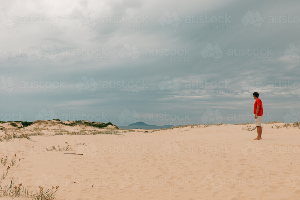 Man exploring sand dunes at Mungo Beach on the NSW coast - Australian Stock Image