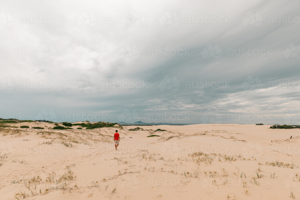 Man exploring sand dunes at Mungo Beach on the NSW coast - Australian Stock Image