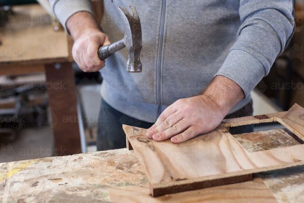 Man hammering a nail at a Men's Shed - Australian Stock Image