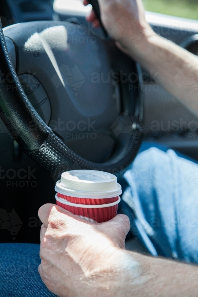 Man holding a coffee in a takeaway cup while driving - Australian Stock Image