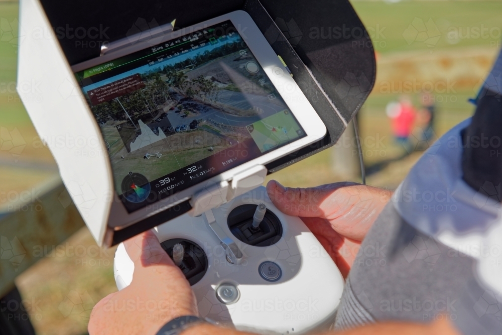 Man holding a white controller with aerial views visible flying his drone, uav, rpas - Australian Stock Image