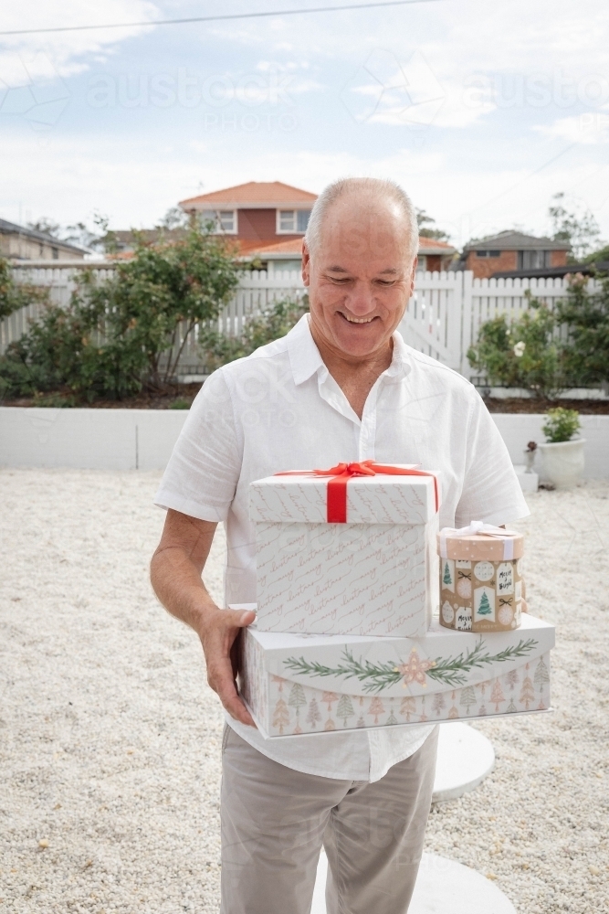 Man holding Christmas presents in front yard - Australian Stock Image