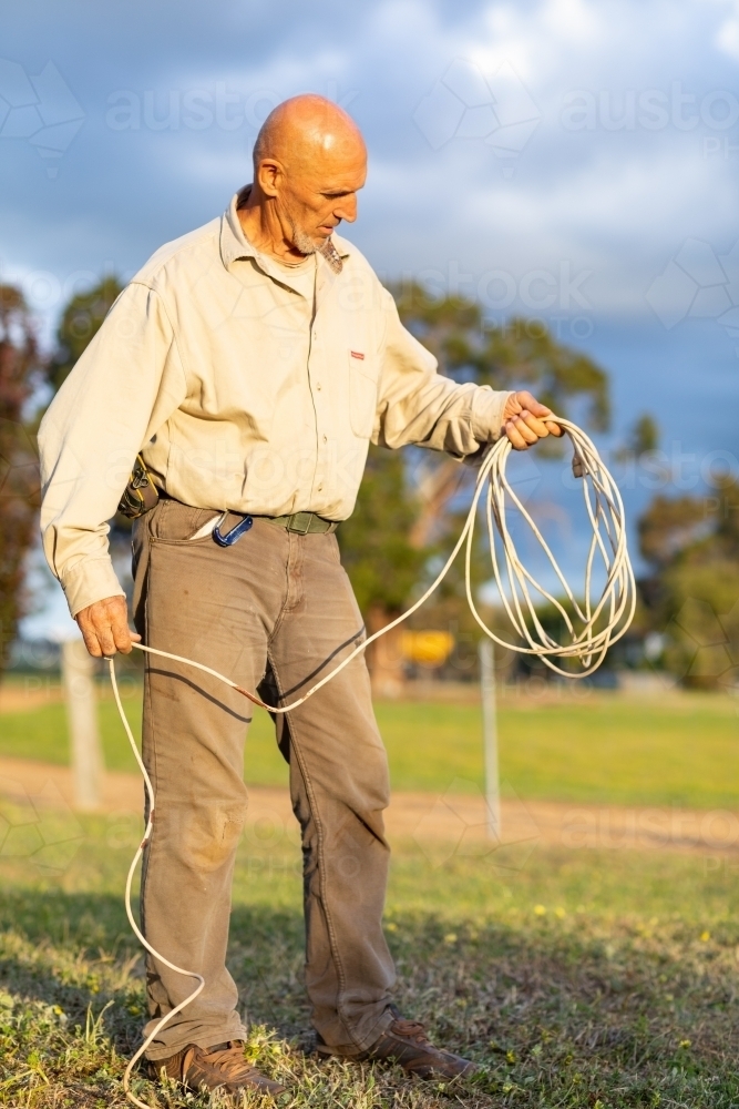man holding electrical extension cord like a lasso - Australian Stock Image