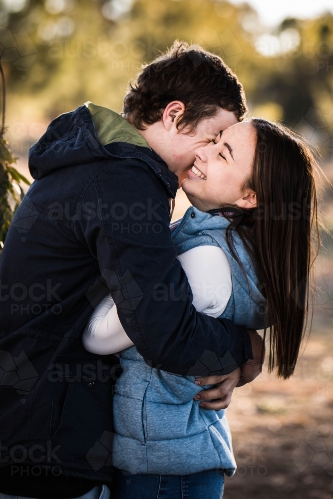 Man holding girlfriend tight in his arms making her laugh - Australian Stock Image