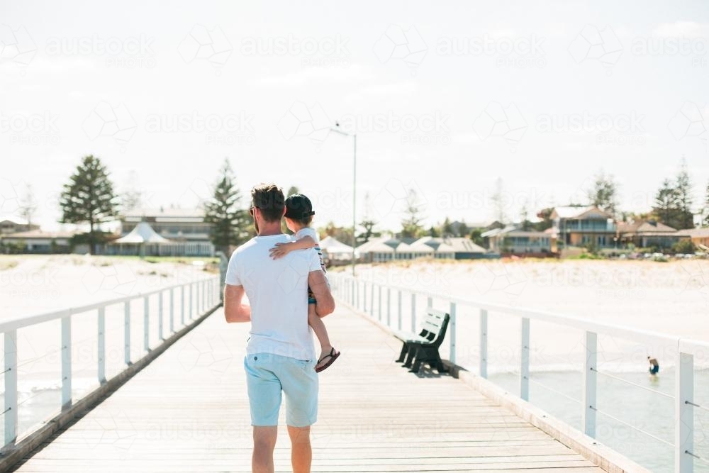 Man holding onto toddler walking on a jetty - Australian Stock Image