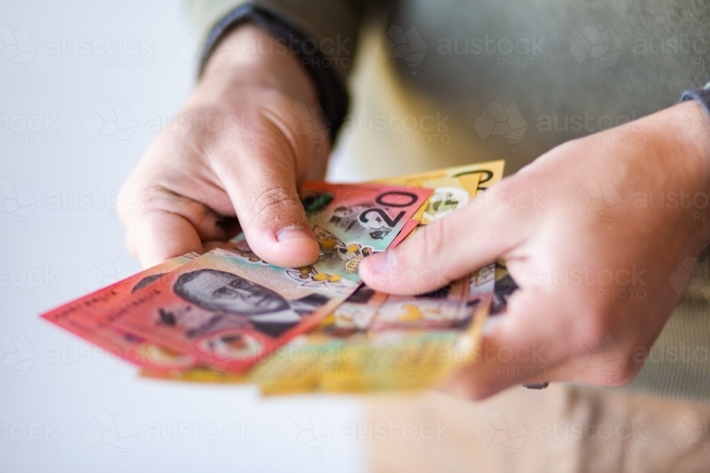 Man holding out fifty and twenty dollar notes australian currency - Australian Stock Image