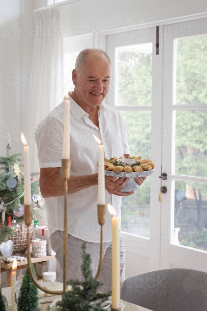 Man holding platter of pastries at Christmas table - Australian Stock Image
