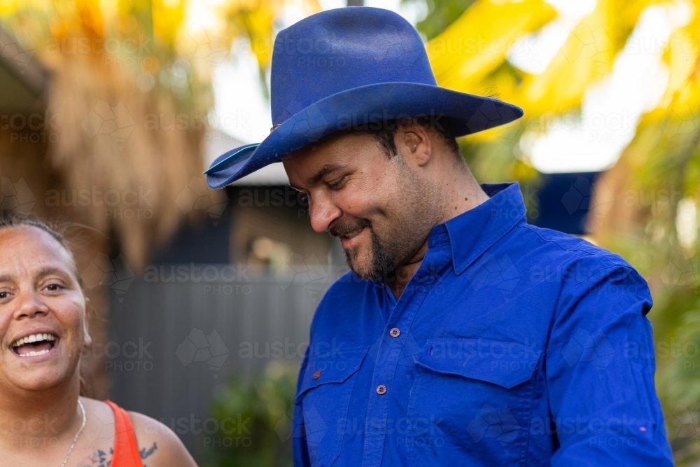 man in blue hat and shirt with woman laughing - Australian Stock Image