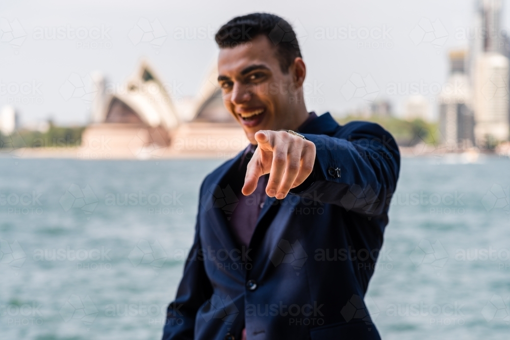 Man in dark blue suit standing outdoors pointing its index finger - Australian Stock Image