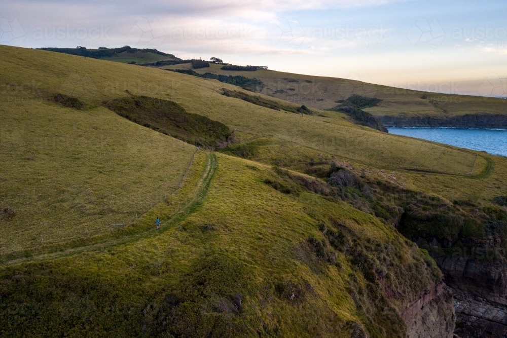 Man in Distance Running Along Cliff Edge - Australian Stock Image