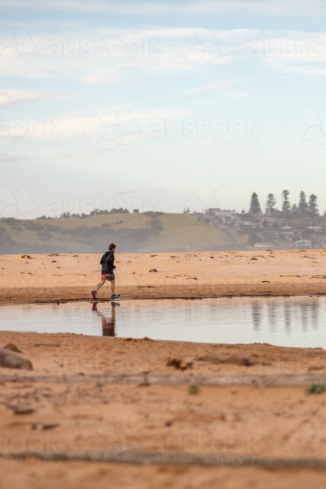 Man in Distance Running on Beach - Australian Stock Image