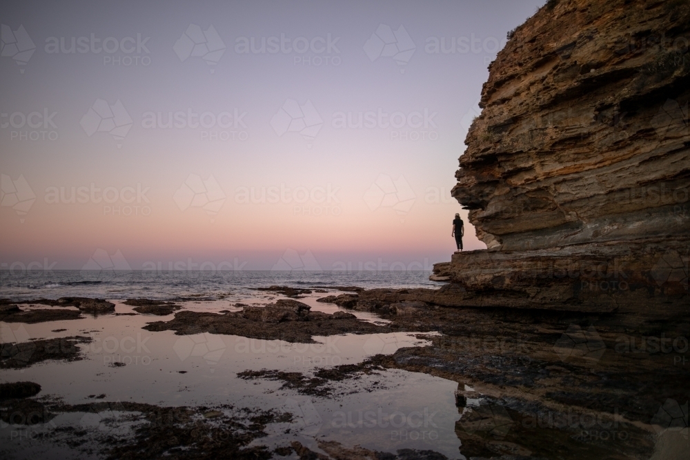 Man in Distance Standing on Rocks Overlooking The Ocean - Australian Stock Image