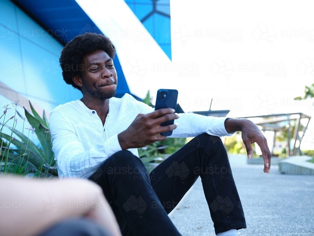 man in front of a blue building using a phone - Australian Stock Image