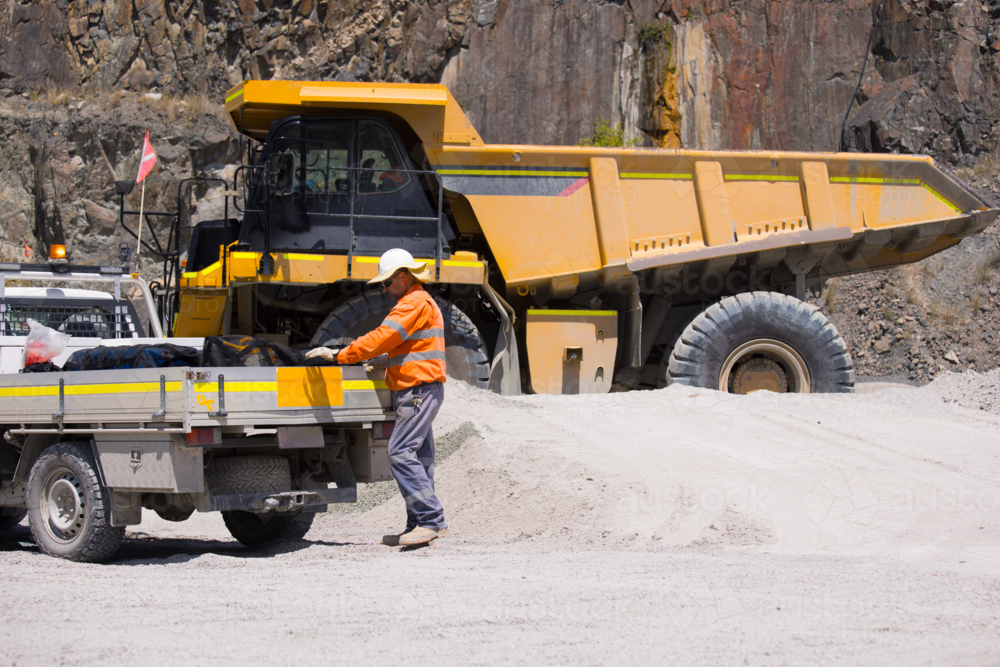 Man in high visibility clothes standing at the back of ute on mine site - Australian Stock Image