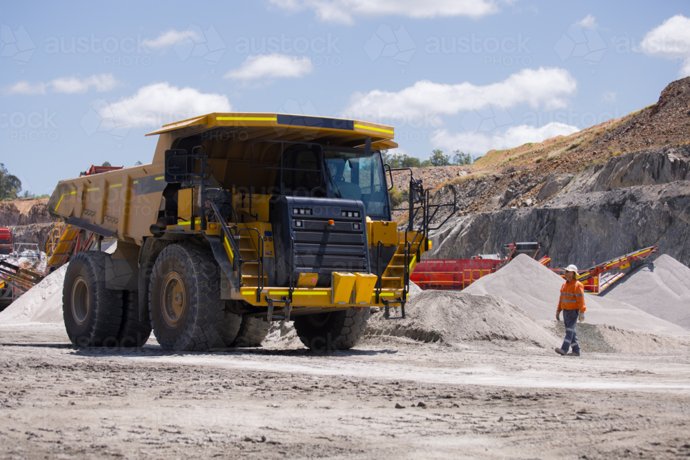 Man in high visibility clothes walking towards the dump truck. : Austockphoto Man in high visibility clothes walking towards the dump truck. - Australian Stock Image