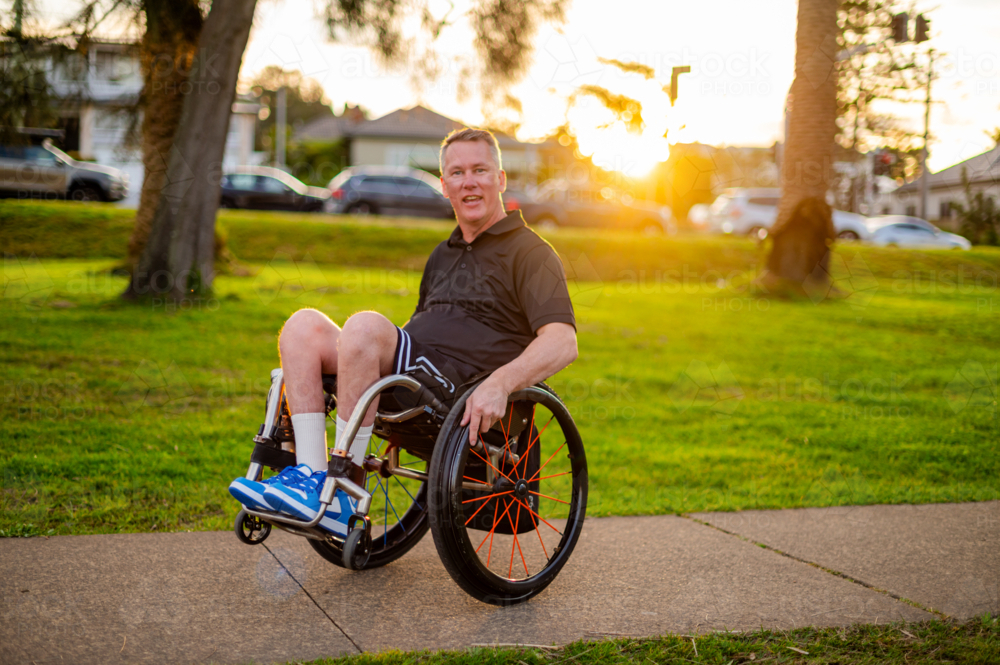 Man in wheelchair smiles while doing tricks on his wheelchair - Australian Stock Image
