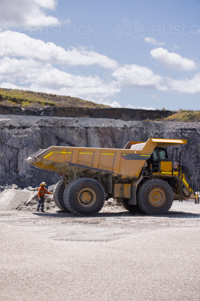 Man in workwear checking the back end of the hauler dump truck on mine site - Australian Stock Image