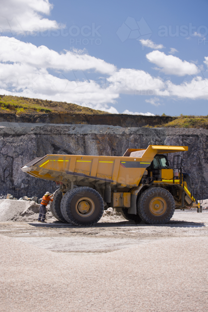 Man in workwear checking the back end of the hauler dump truck on mine site - Australian Stock Image