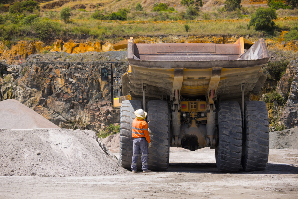 Man in workwear checking the rear wheel of the hauler truck. - Australian Stock Image
