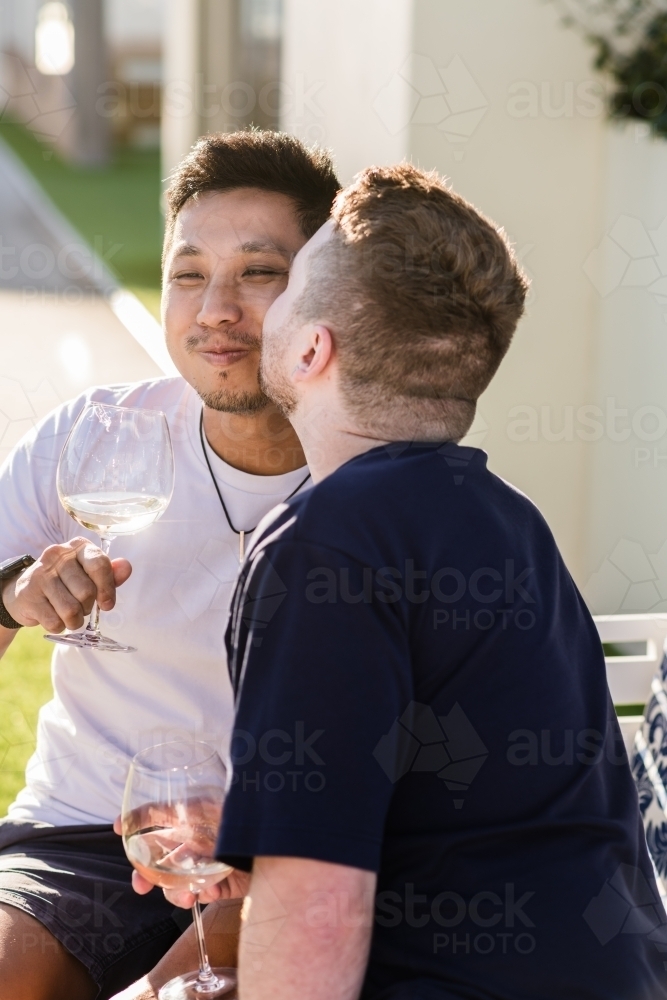 Man kissing his boyfriend on the cheek - Australian Stock Image