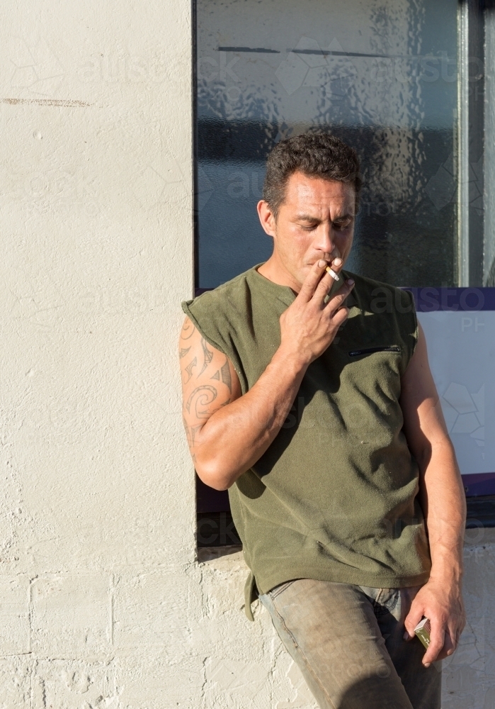 Man leaning against a wall and smoking - Australian Stock Image