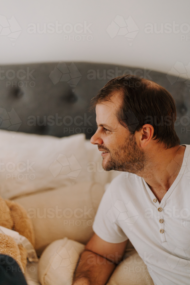 Man leaning on bed looking off-camera - Australian Stock Image