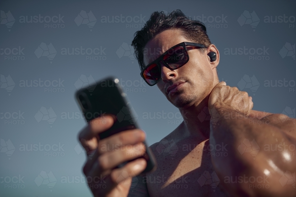 Man listening to music on phone while exercising - Australian Stock Image