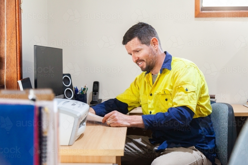 Man looking at paperwork in home office - Australian Stock Image