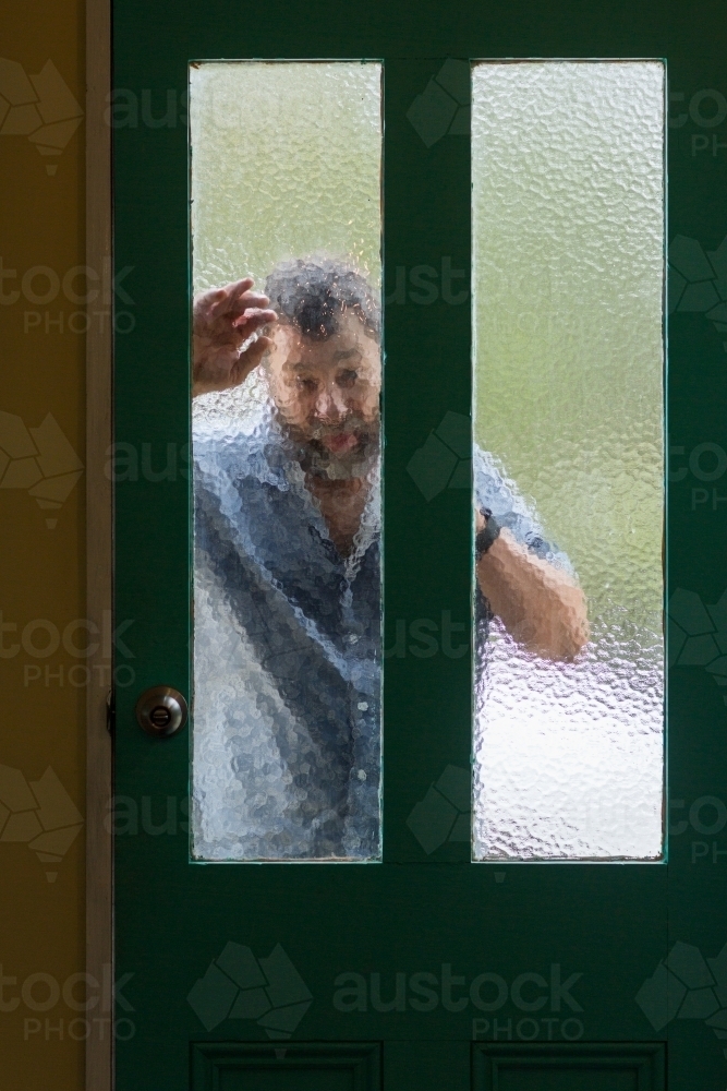 Man looking in through frosted glass door - Australian Stock Image
