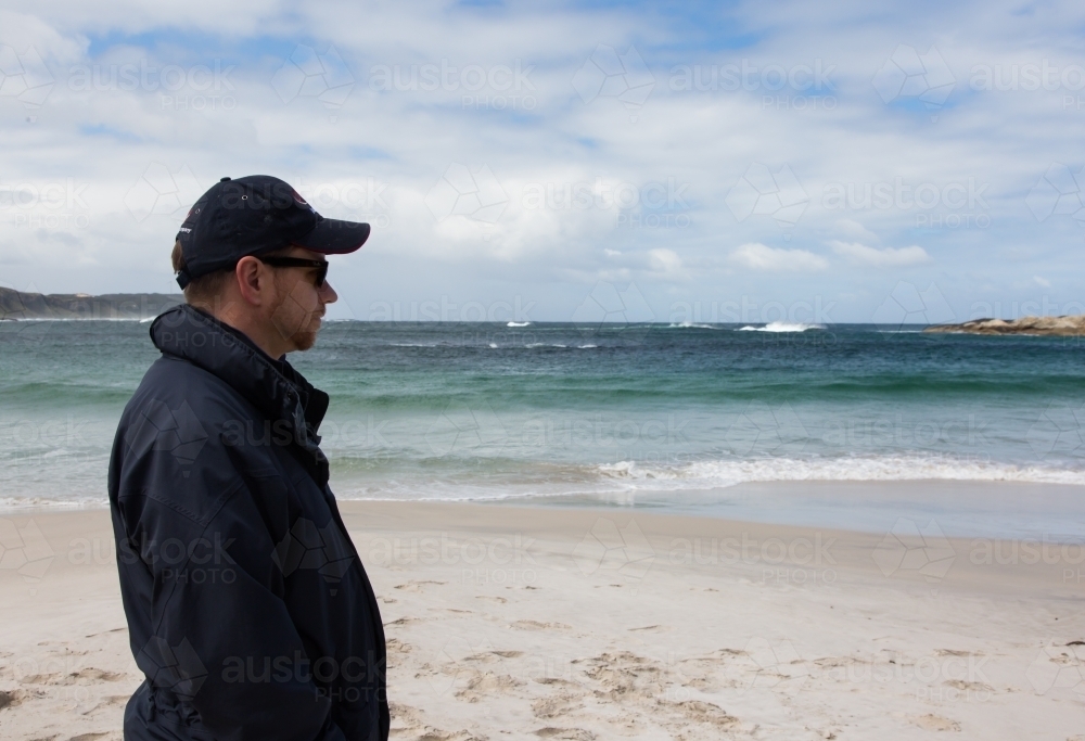 Man looking out over the beach and ocean - Australian Stock Image