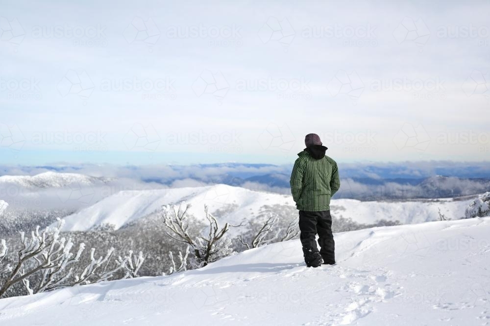 Man looking over snow mountains - Australian Stock Image