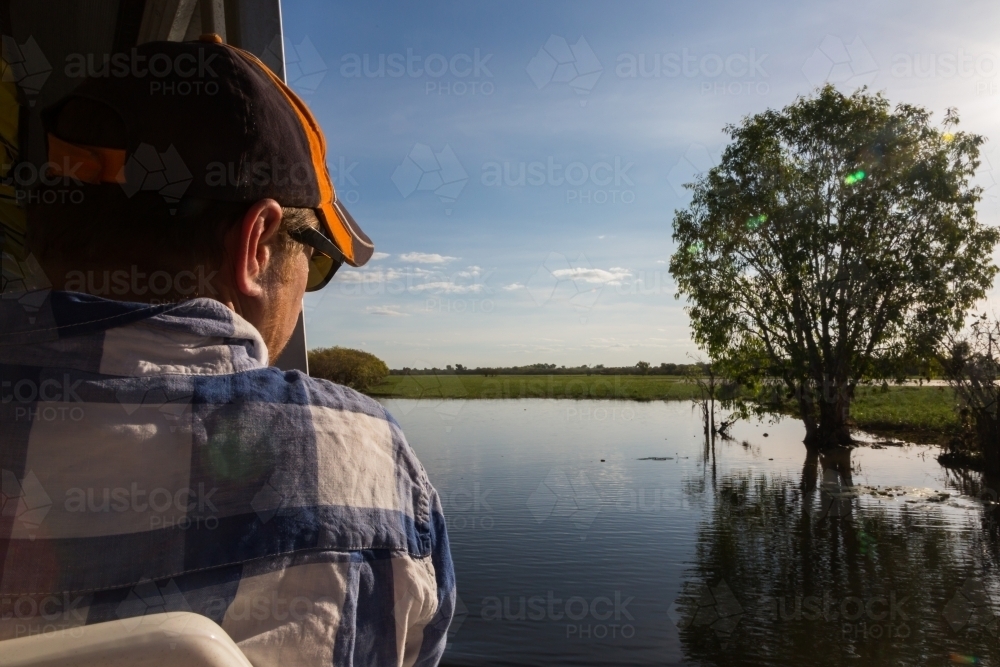 man on a boat cruise looking over a waterway in kakadu - Australian Stock Image
