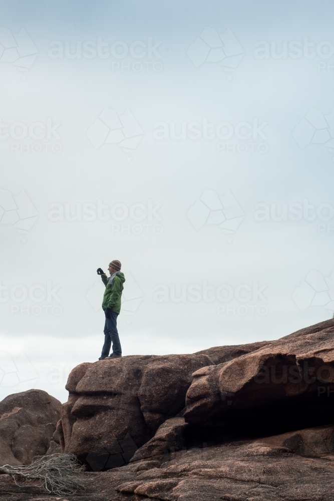 Man on boulder rocks at beach - Australian Stock Image