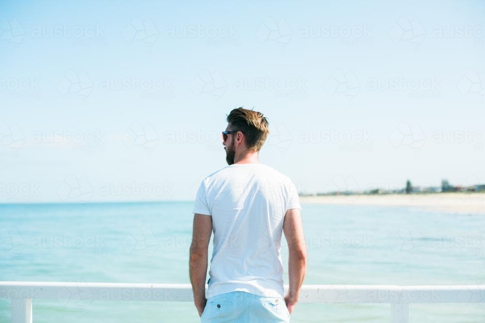 Man on jetty overlooking a beach - Australian Stock Image