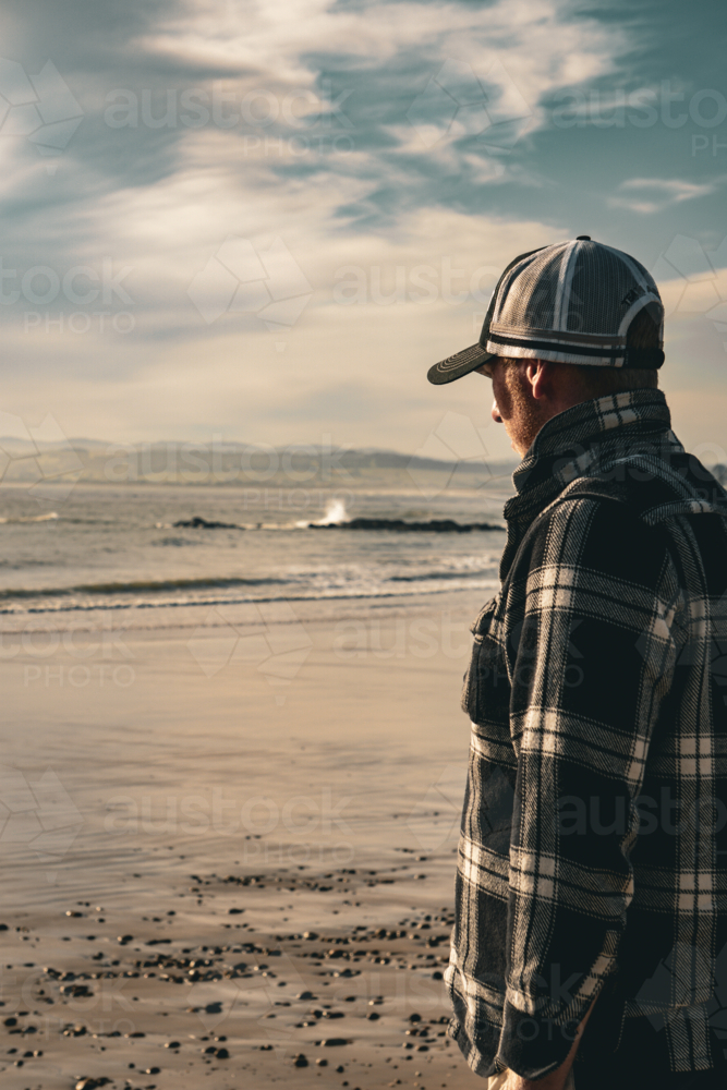 Man overlooking the ocean, wearing a cap - Australian Stock Image