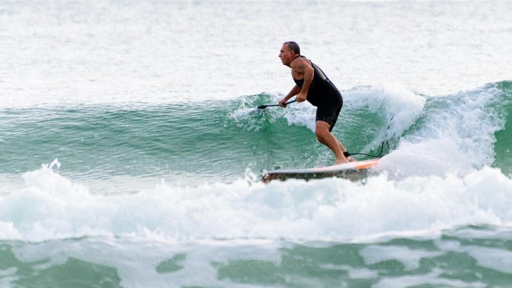 Man paddleboarding on waves - Australian Stock Image