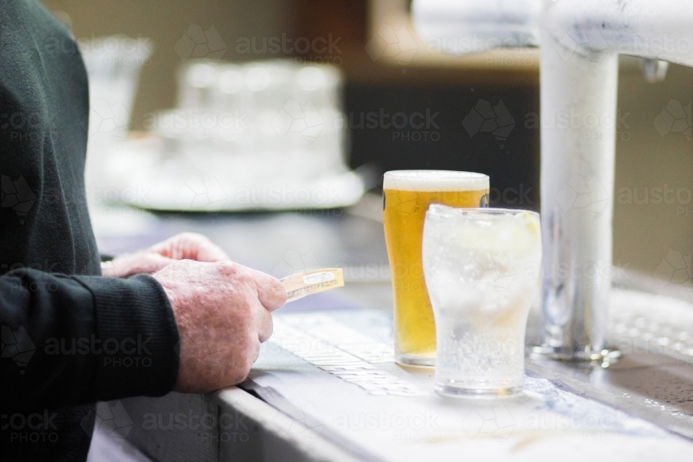 Man paying for glass of beer at the bar - Australian Stock Image