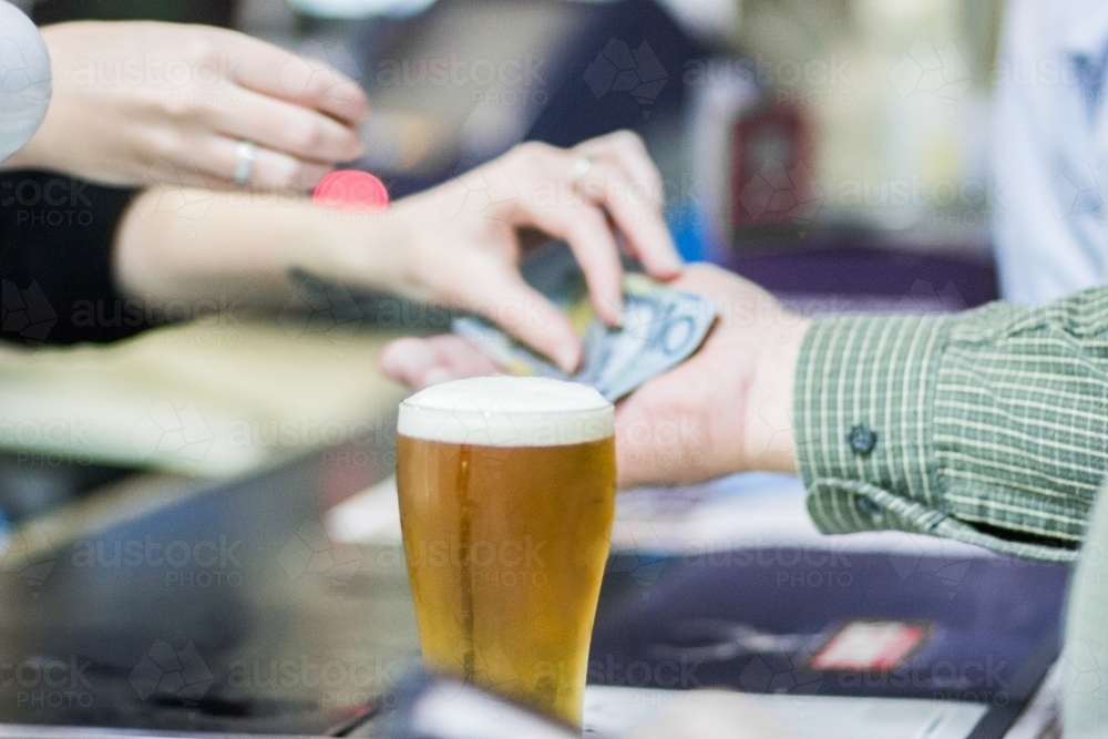 Man paying for glass of beer at the bar - Australian Stock Image