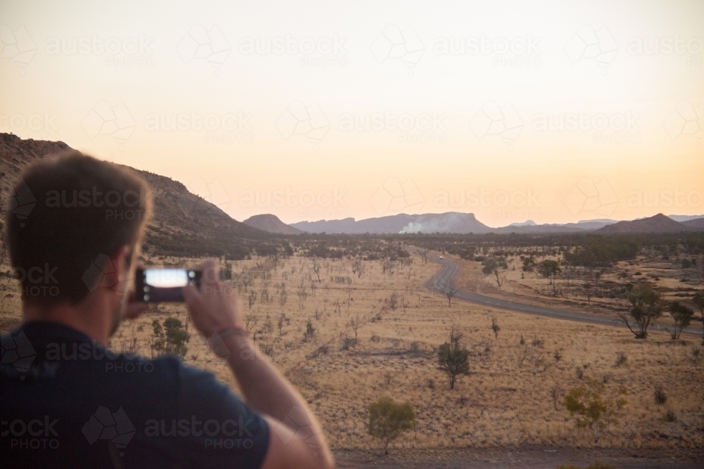 Man photographing outback landscape at dusk - Australian Stock Image