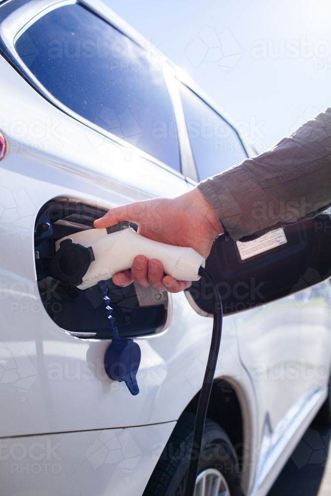 Man Plugged In Image of Man plugging in Hybrid vehicle electric charging plug into ...