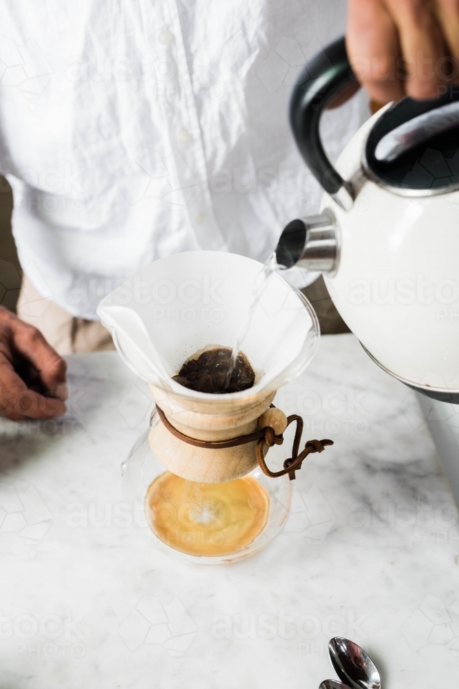 Man pouring boiling water from kettle into pour over coffee - Australian Stock Image