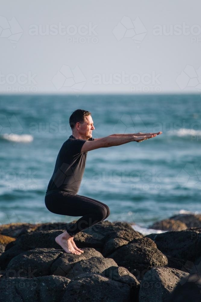 Man practising Yoga poses at the beach - Australian Stock Image