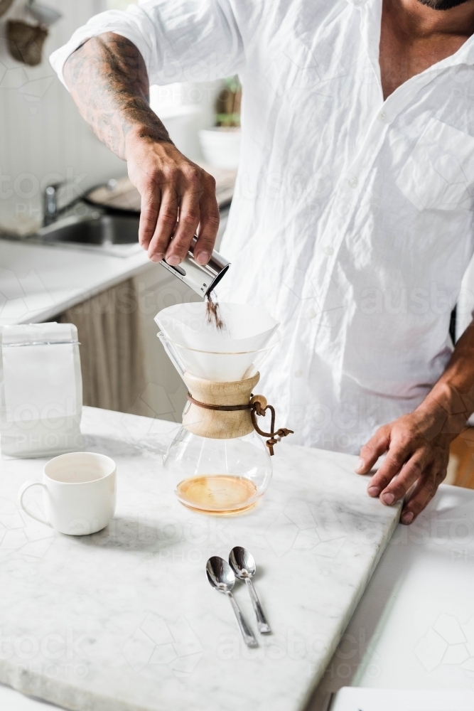 Man preparing a pour over coffee in his kitchen - Australian Stock Image