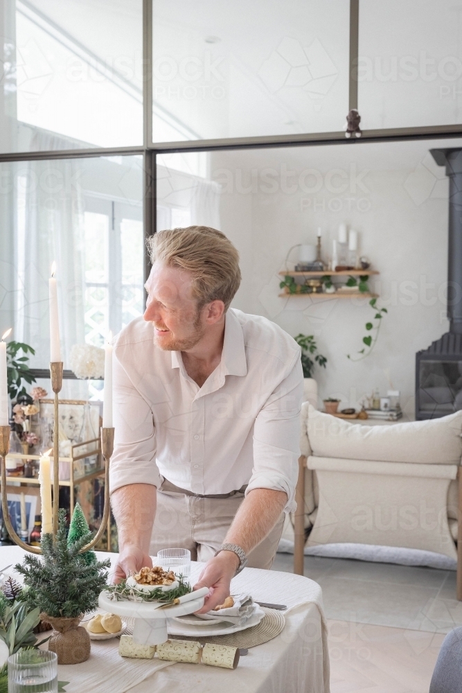 Man preparing table with Christmas decorations - Australian Stock Image