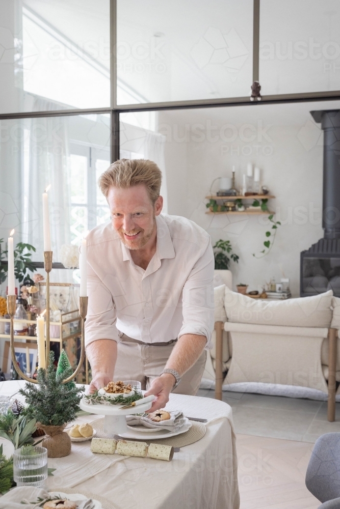 Man preparing table with Christmas decorations - Australian Stock Image
