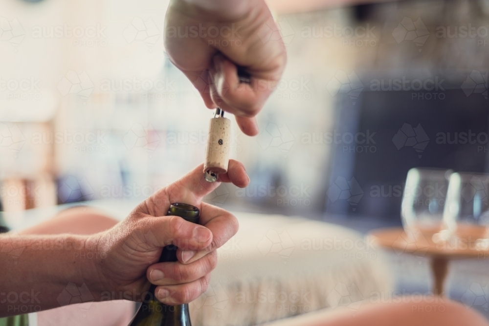 man pulling cork from wine bottle - Australian Stock Image