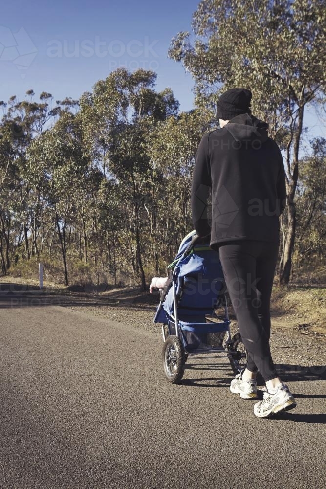 Man pushing a toddler in a stroller on a country road - Australian Stock Image
