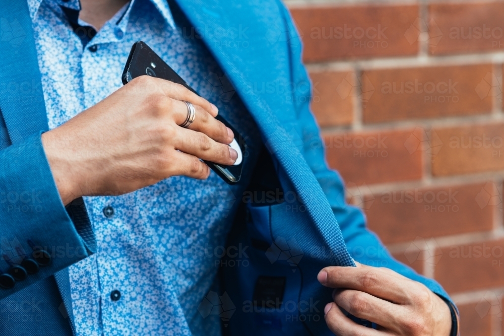man putting phone into jacket pocket - Australian Stock Image