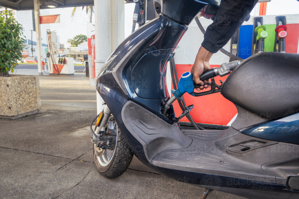 Man refueling his scooter at the servo - Australian Stock Image